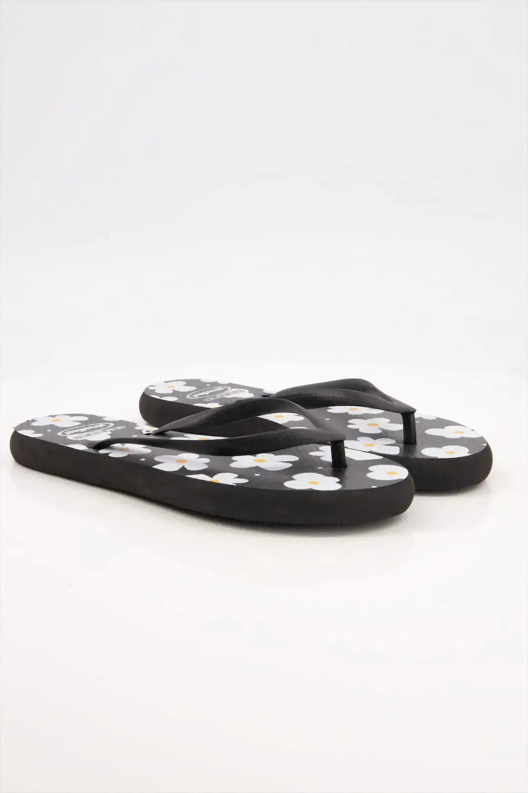 Street Feet's Flower Design Flip-Flops in black sole and white flowers, featuring soft soles and durable rubber straps for maximum comfort. Lightweight and breathable, ideal for casual wear.