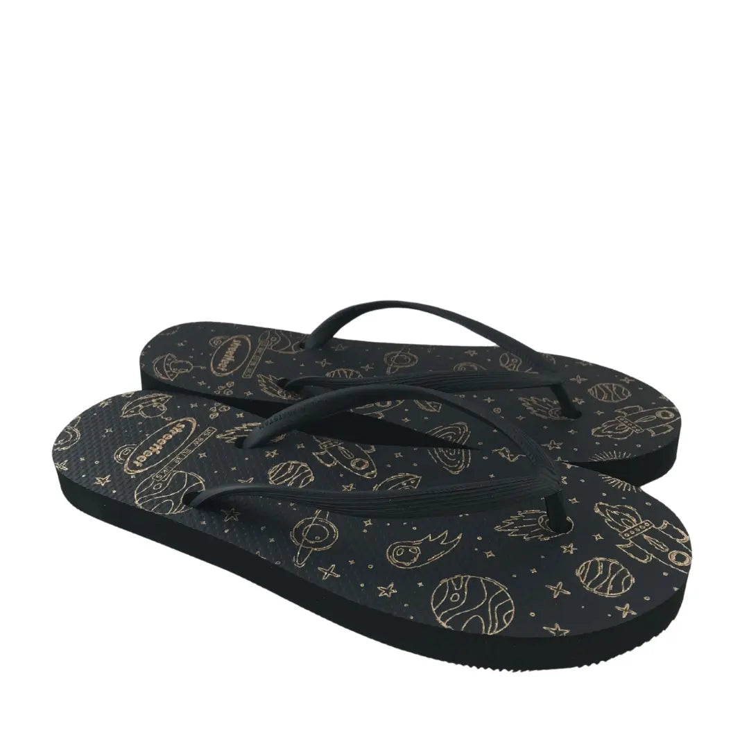 Ladies flip flops with celestial gold rocket and planet design on a dark background from Streetfeet

